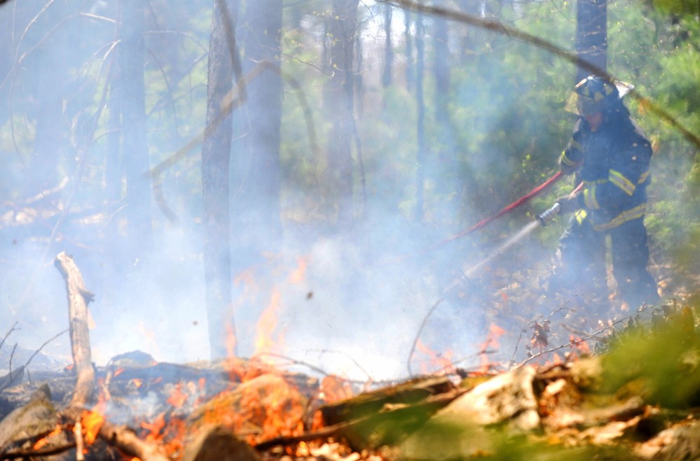 Jonathan Berringer, a firefighter with the Winslow fire department, battles a grass fire on Morrill Road in Winslow on Tuesday.