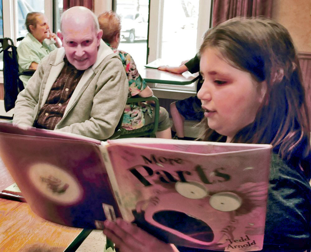 Quimby School student Lacie Sanipas reads to Somerset Rehab and Living Center resident Wilmont Robinson at the Bingham facility on Tuesday. Students participating in “Screen Free” week don’t use electronic devices and instead go outdoors and engage with community members.