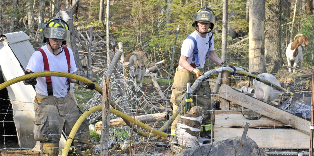 Goats watch as firefighters remove a hose after a barn fire Thursday at 26 Long Acres Road in Mount Vernon.