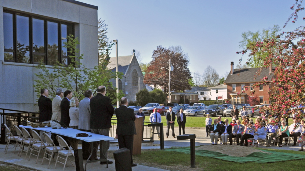 People sit on chairs listening to speeches on Thursday during a ceremonial groundbreaking for Lithgow Library expansion in Augusta. The part of the building at top left will be demolished, and the new expansion will be built onto the grass and parking lot seen in the background.