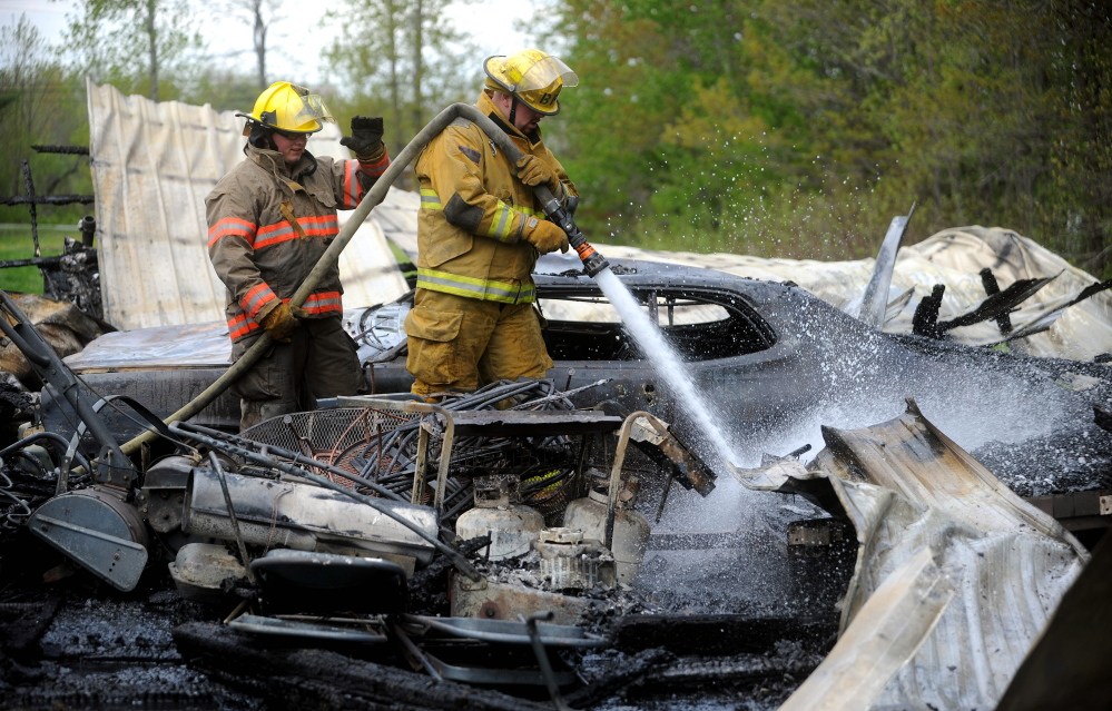 Kyle King with the Burnham fire department, right, and Ryan-Michael Havery with the Pittsfield fire department, mop up a garage fire on Webb Road in Pittsfield on Saturday. Firefighters were dispatched around 1:30 in the afternoon. The garage was a total loss.