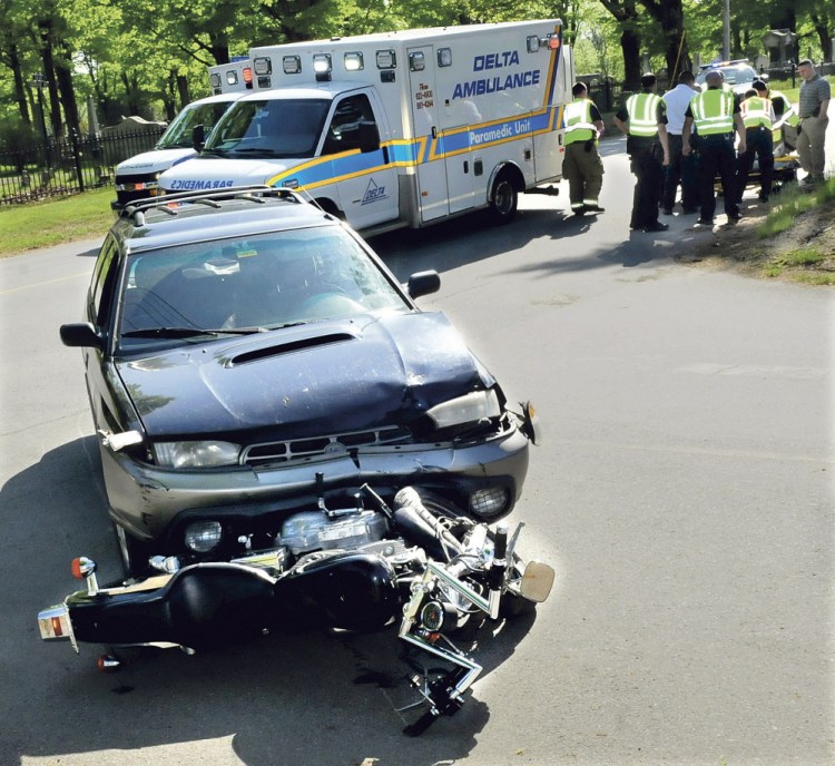 Ambulance personnel treat a seriously injured motorcycle operator who collided with a vehicle on Grove Street in Waterville late Tuesday afternoon.