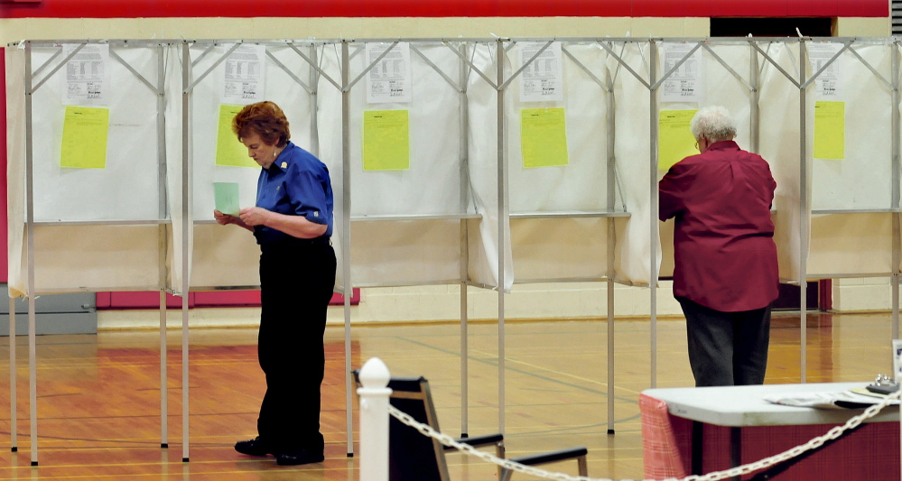 Sue Fisher, left, double-checks her ballot during voting on the Regional School Unit 18 school budget Tuesday in Oakland. Residents in Oakland, Belgrade, China, Rome and Sidney turned down the budget plan in the referendum, 747-619.