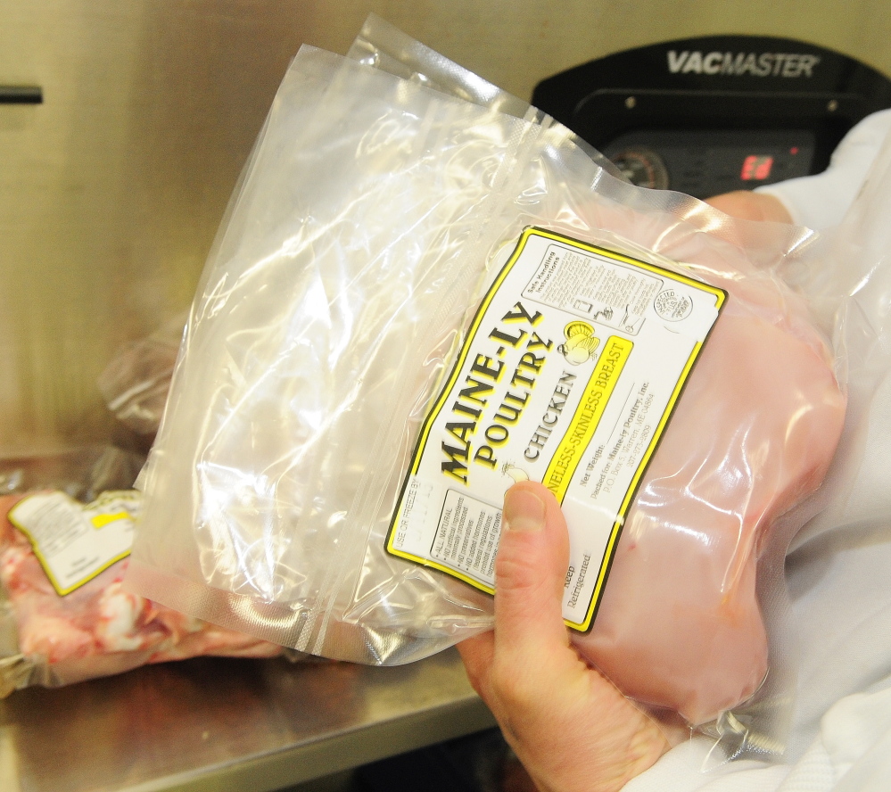 Co-owner and manager Gina Simmons takes chicken breasts out of a vacuum sealer March 5 at Common Wealth Poultry Co. in Gardiner.