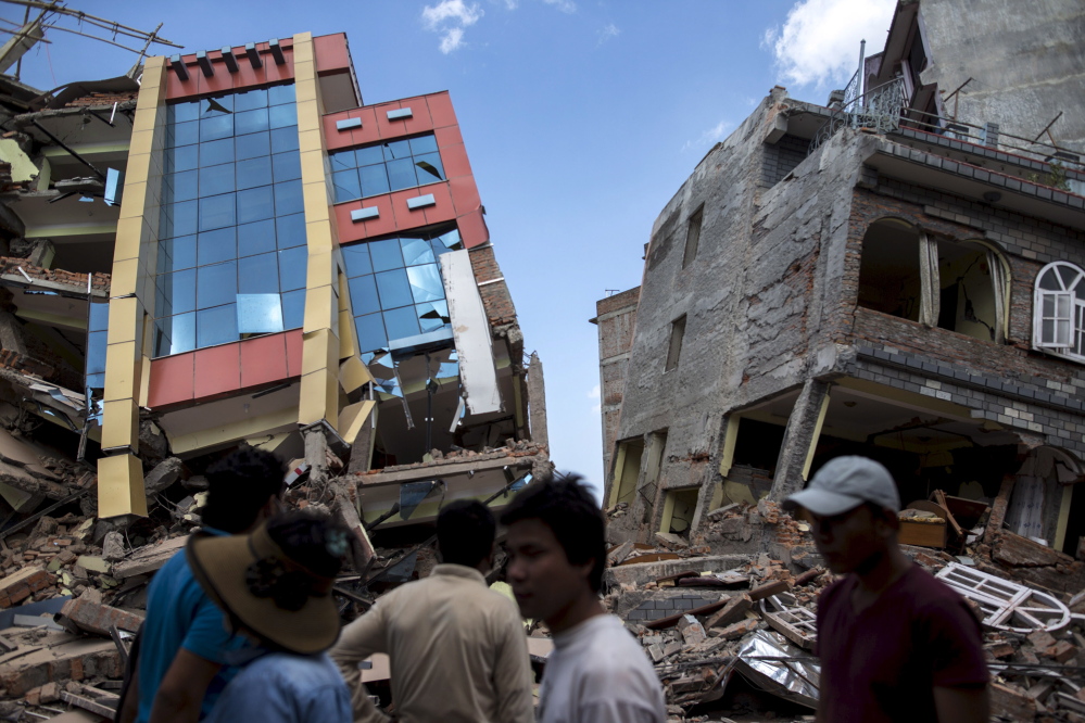 People walk near a pair of damaged buildings after a 7.3-magnitude earthquake struck in Kathmandu, Nepal, on Tuesday. Dozens more were reported killed in the latest jolt, which spread panic among residents following the devastating quake less than three weeks ago.
