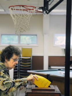 Mary Alice Cook votes beneath the hoops Tuesday at the Ladd Recreation Center in Wayne. Voters in town were determining the fate of a large parcel of land that abuts Wilson Pond.