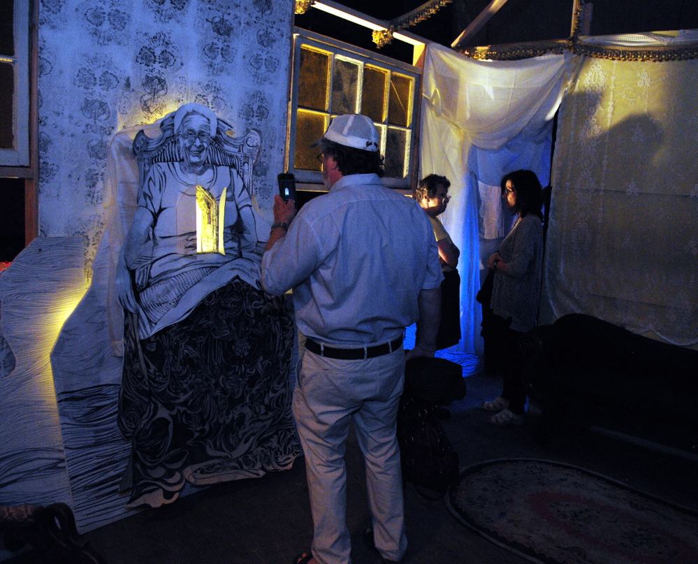 People walk through the Colonial Theater to see the opening of “Home/Resilience,” a documentary installation about aging, wisdom and home that opened Friday at the long-unused theater in downtown Augusta. The installation is a collaborative work by Maine artists Caroline Losneck, Chris Byron and Kelly Rioux.