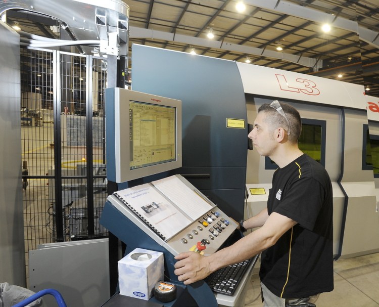 Operator Maurizio Cigarini sets up one of the high-tech laser machines that will help produce many of the parts at Modula storage products.