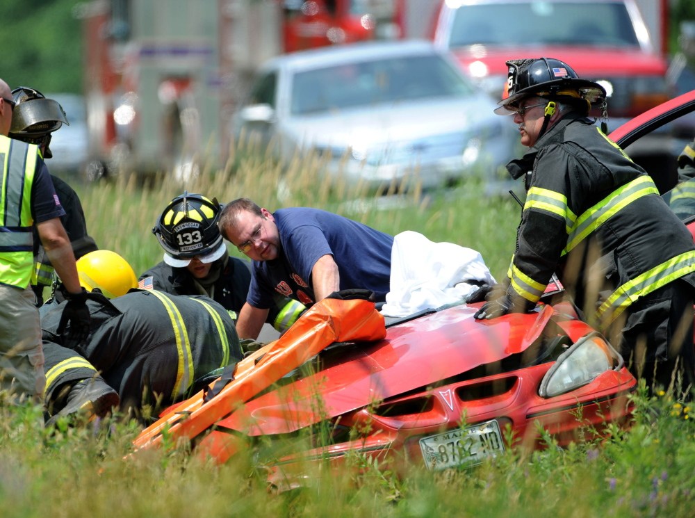 Rescue workers from Madison and Skowhegan fire departments work to extricate a woman from her sedan on Lakewood Road in Madison on Monday.