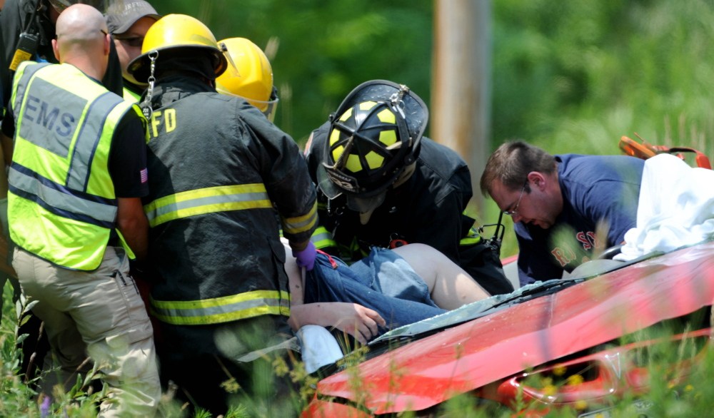 Rescue workers from Madison and Skowhegan fire departments work to extricate a woman from her sedan on Lakewood Road in Madison on Monday.