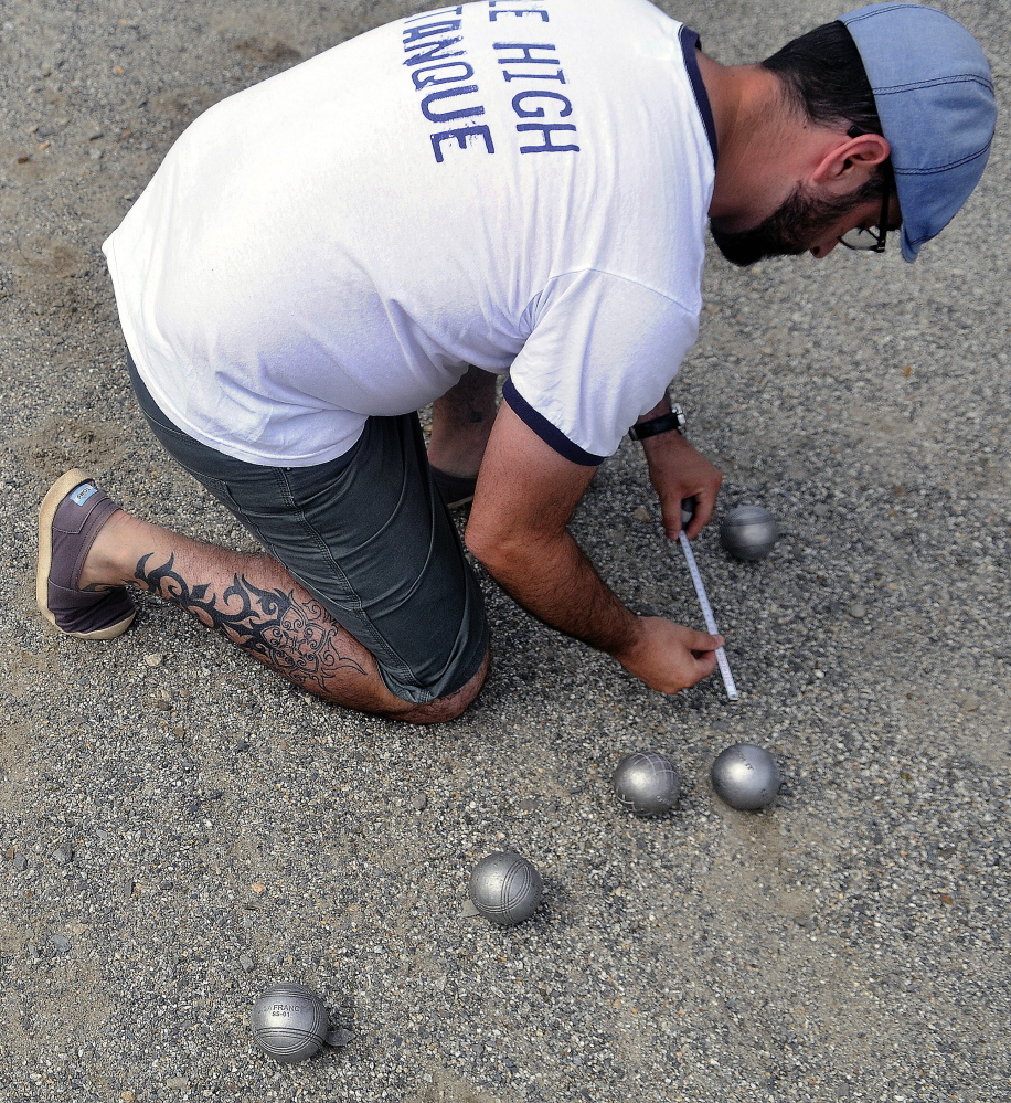 Stephen Lessard, of Denver, Colo., measures the distance between petanque balls Sunday during an annual tournament at Mill Park in Augusta.