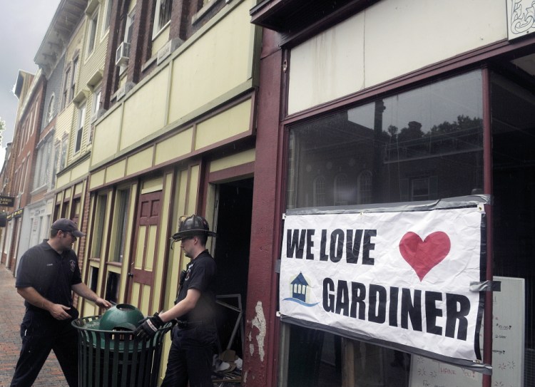 Gardiner firefighters replace a trash can blocking an entrance to 235 Water Street on Sunday after searching for tools lost in the blaze that destroyed the structure last Thursday.