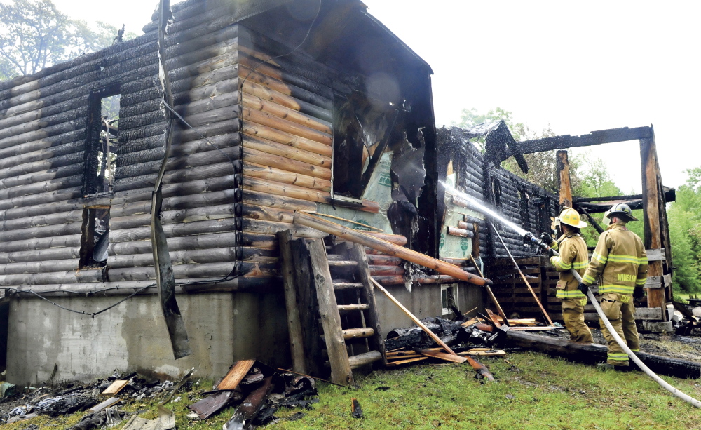 Winslow firefighters Capt. Kevin Fredette, left, and Waylon Capp hose down hotspots to the home of Franklin and Paula Richards that was destroyed by fire Monday. The home and garage were destroyed in a fire believed to be caused by a lightning strike.