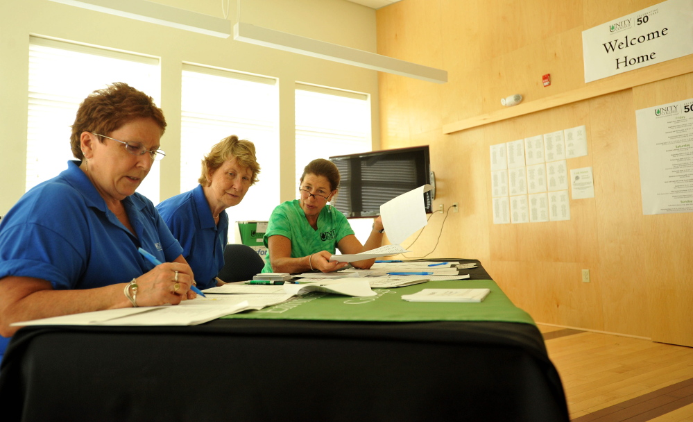 Liz McMahon, class of 1973, left, Arlene Constable Schaefer, center, and Carol Lichtenbaum, prepare for the arrivals of alumni and college friends on Friday at Clifford Hall for the 50th anniversary of Unity College.