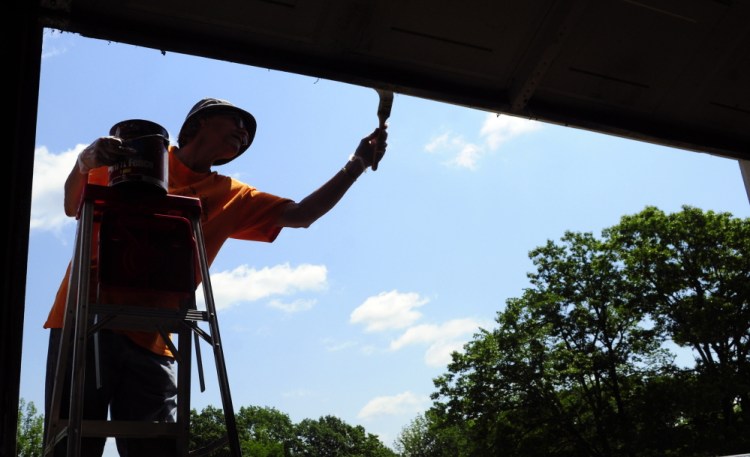 Joy Buzzell paints the door frame of the museum building on Tuesday at the Monmouth Fair grounds.