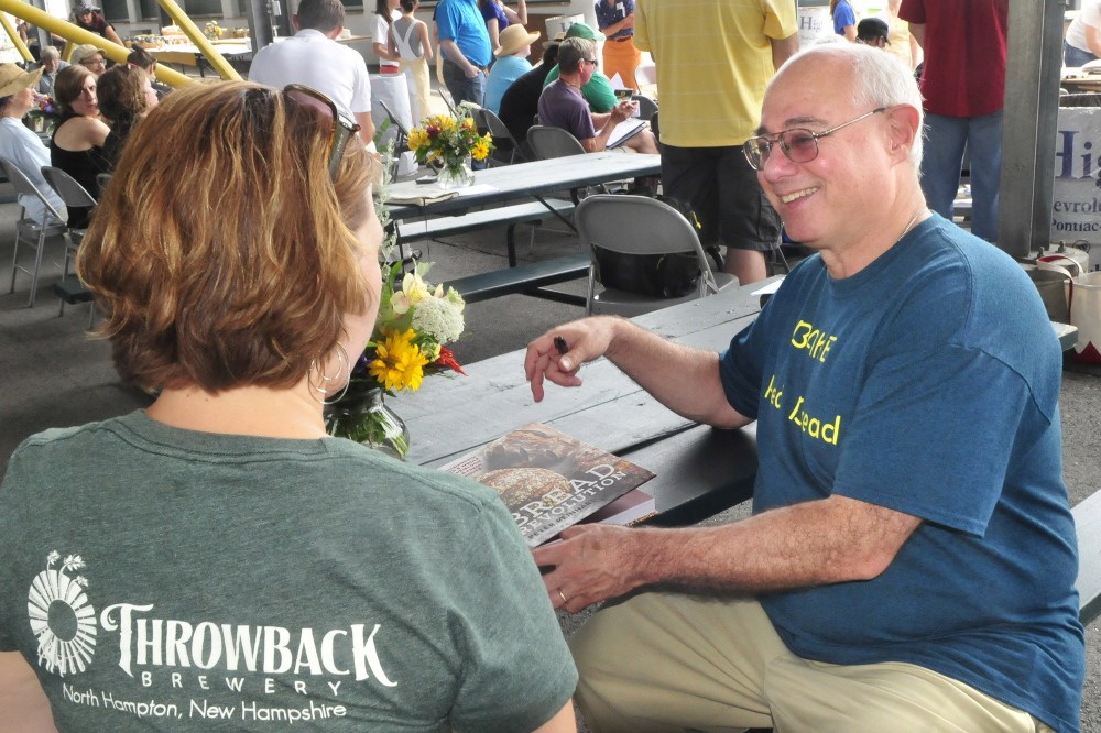 Chef and keynote speaker Peter Reinhart autographs his book “Bread Revolution” for Erin Allgood at the ninth annual Kneading Conference in Skowhhegan on Thursday.
