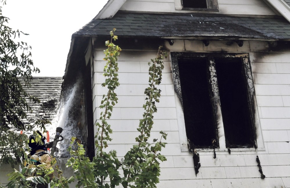 Waterville firefighter Richard Haviland sprays water through a window into the heavily damaged second floor of a home on Silver Street in Waterville on Wednesday. Fire investigators Friday were still trying to determine the cause.