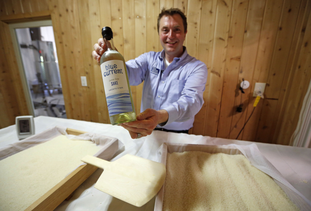 Dan Ford, founder of the Blue Current Brewery, poses with a bottle of sake at the brewery in Kittery.