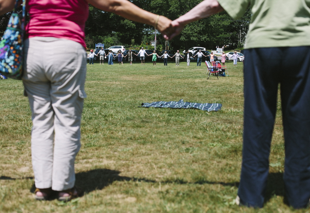 Attendees of the vigil for the Jorgensen family gather in a circle and hold hands as a symbol of unity and peace.