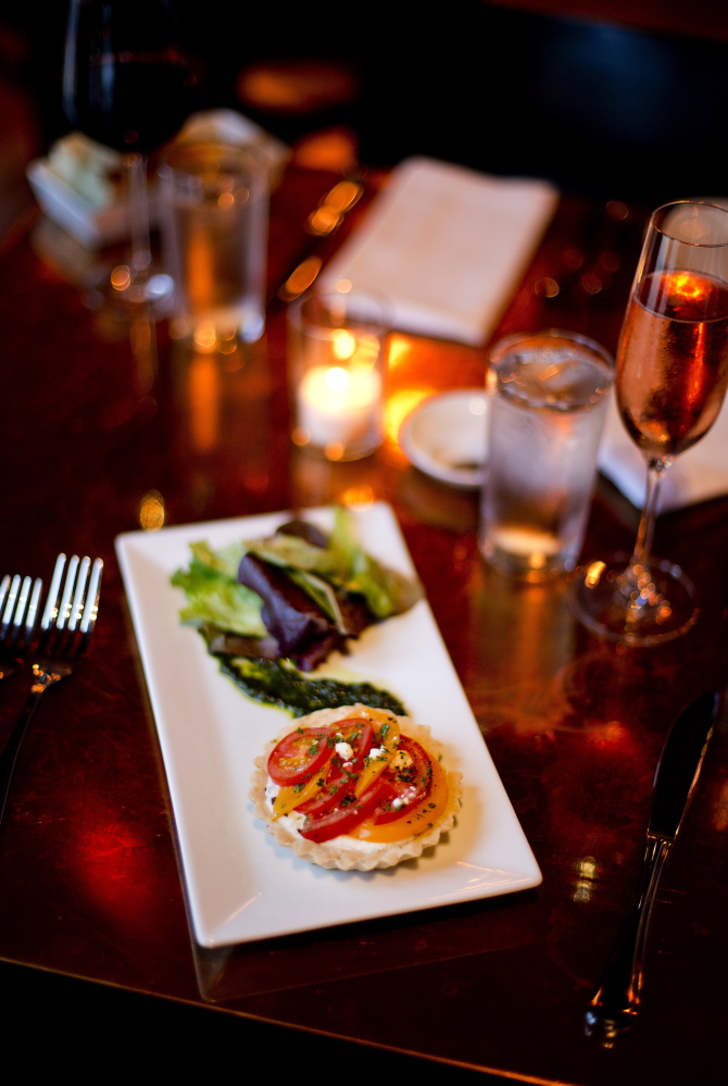 A Summer Tomato Tart with a buttery crust, goat cheese, pistou and farmed baby greens is one of chef Mitch Kaldrovich’s specialties.  Gabe Souza/Staff Photographer