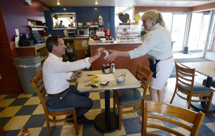 Susie Kiehn-Geary, manager and chief server at the Miss Portland Diner, accepts the signed check from attorney Kaighn Smith of Portland on Thursday. Smith, who used to wait tables himself, said restaurant workers “deserve every penny that they earn.” The customer left a $5 tip on his $9.99 bill.