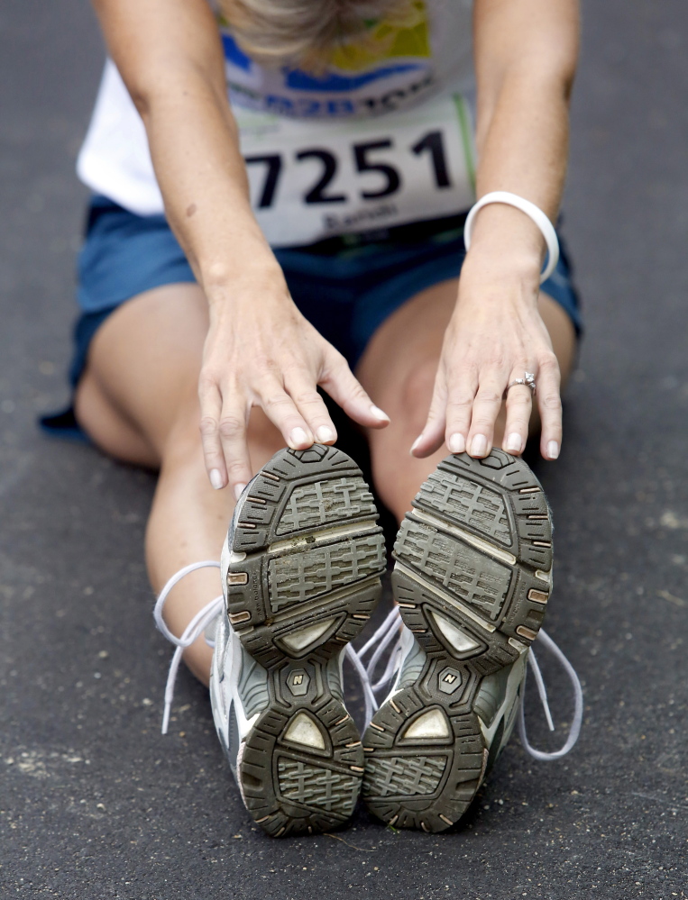 Randi Sheehan of South Portland stretches last August before the start of the Beach to Beacon 10K road race. Even though median finish times are rising steadily, race winners have broken course records four times in the past six years.