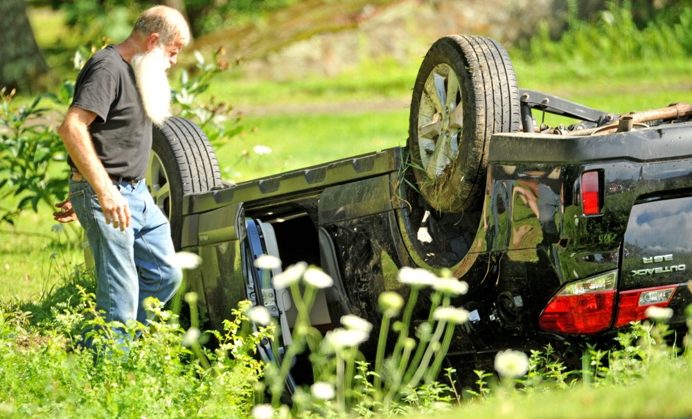 Ken Whittier, of Sidney, collects belongings from a car involved in a collision Saturday on Belgrade Road in Sidney. Whittier was one of the first people at the scene after the accident.