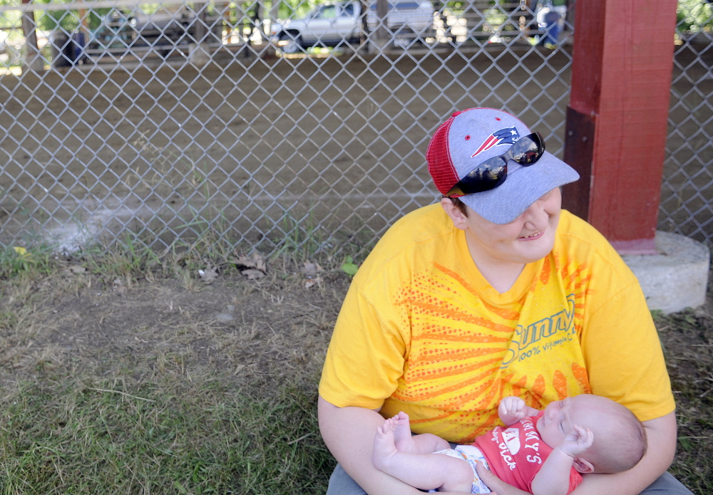 Kristoff Fox, 17, of Monmouth, holds his month-and-a-half old nephew, Jeremiah Fox, of Monmouth, on Sunday outside the pulling ring at the Monmouth Fair. Four generations of Foxes volunteered and attended the agricultural exhibition.