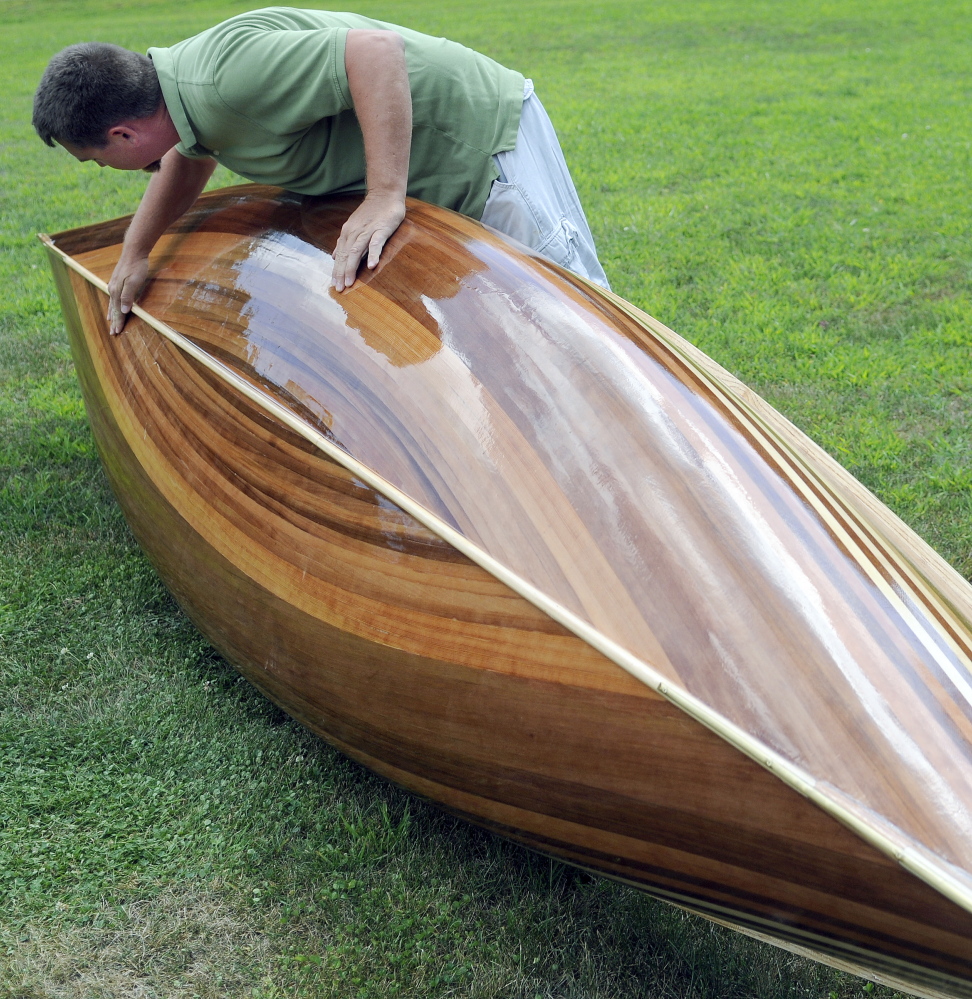 Math teacher Jeromy Jamison inspects the hull of the cedar strip canoe he built with his Hall-Dale middle  and high school students at his home in Windsor.