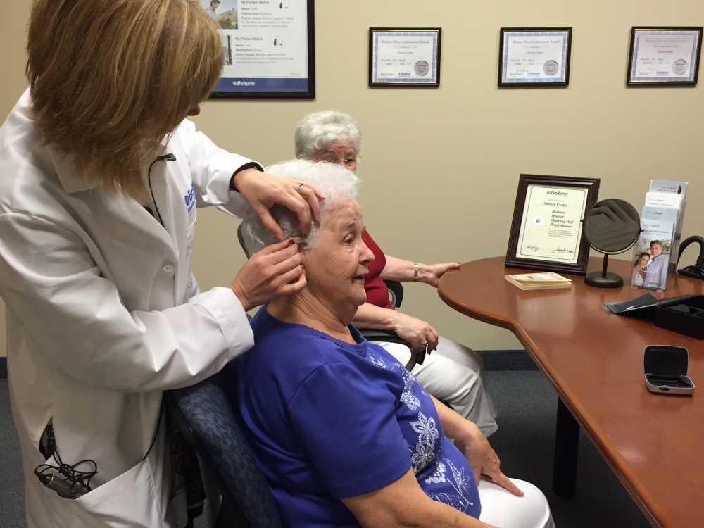 Felicia Curtis, hearing instrument specialist from Beltone New England’s Waterville Office, fits Joyce Morisette, of Waterville, with new hearing aids from The Beltone Hearing Care Foundation. Behind Morisette is her friend, Connie Francoeur, who helped Morisette get the hearing aids through Beltone’s Hearing Care Foundation.