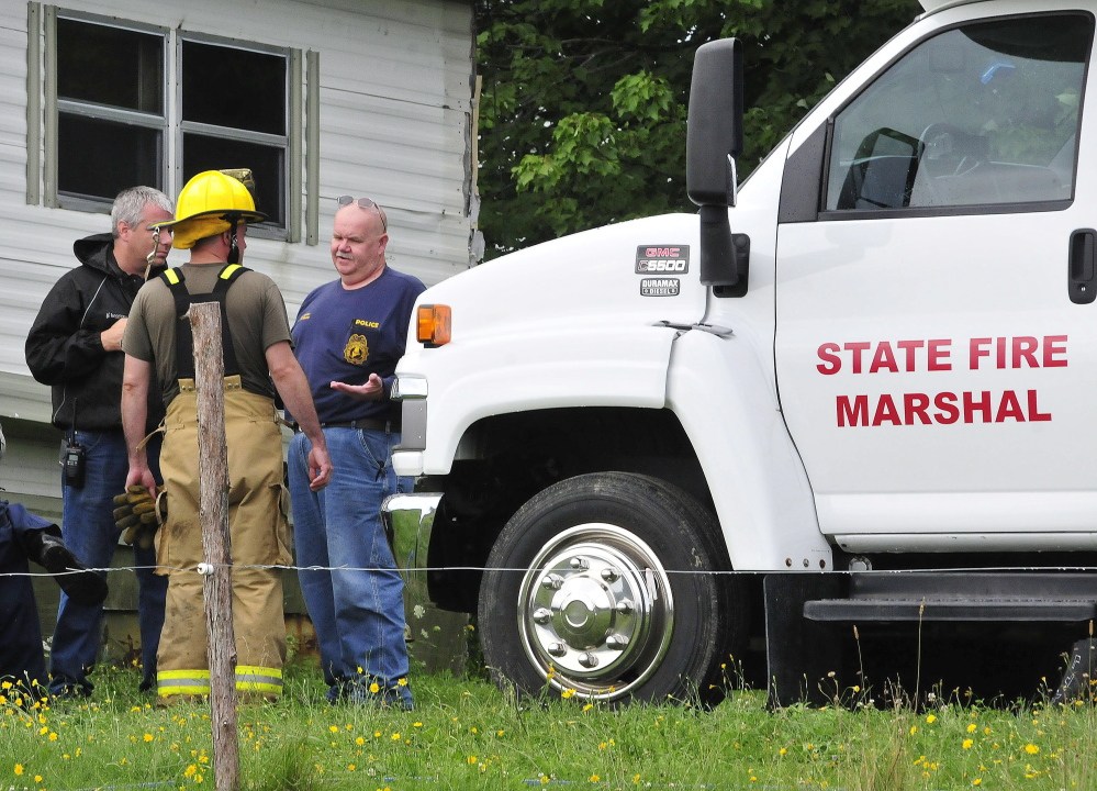 Investigator Kenneth MacMaster, right, of the Office of the State Fire Marshal, speaks with Oakland fighters outside the burned mobile home at 146 Ten Lots Road in Oakland on Sunday. A male occupant was reportedly transported to the hospital with serious injuries.