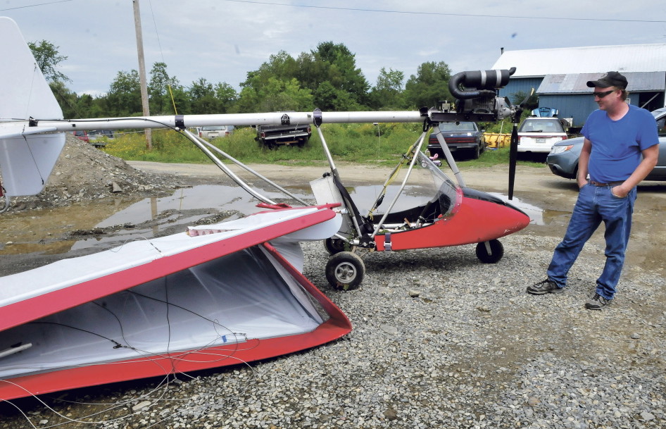 Steve Rackliff surveys his experimental aircraft on Sunday near his home in Starks. Rackliff was on his maiden flight Saturday evening when the plane lost power and crashed into trees. The plane sustained serious damage but Rackliff escaped injury.