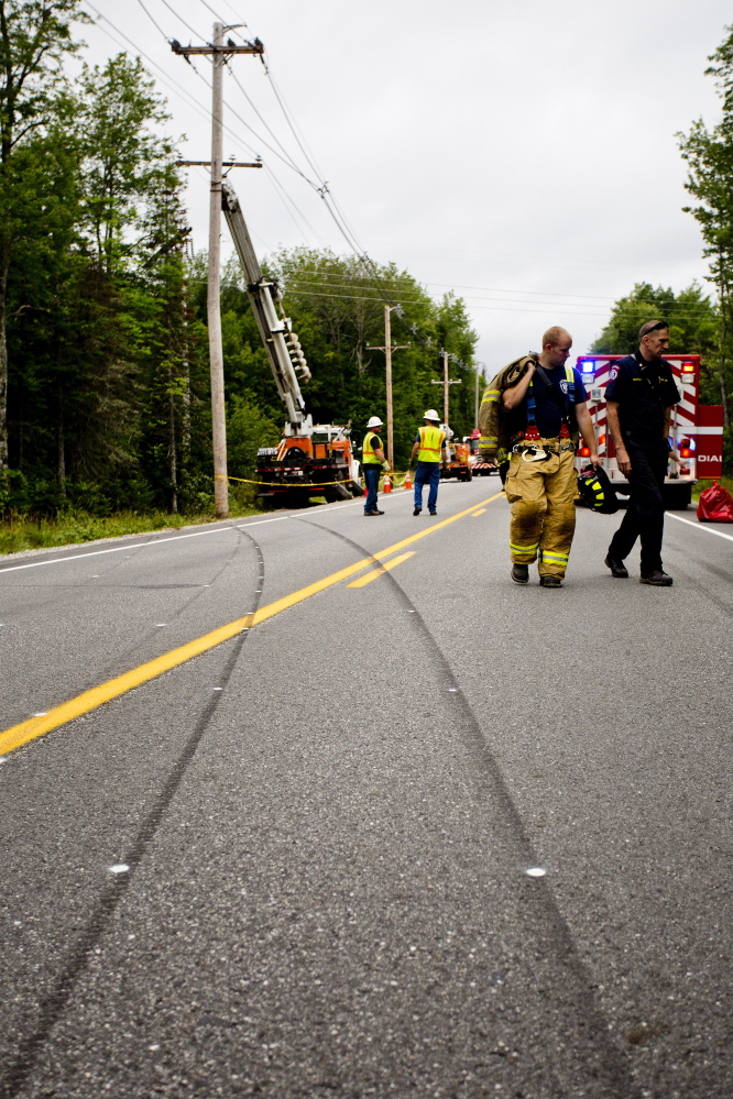 Emergency personnel walk past tire skid marks that lead straight to the utility pole that a vehicle struck while traveling on Route 11 in Casco on Tuesday morning.