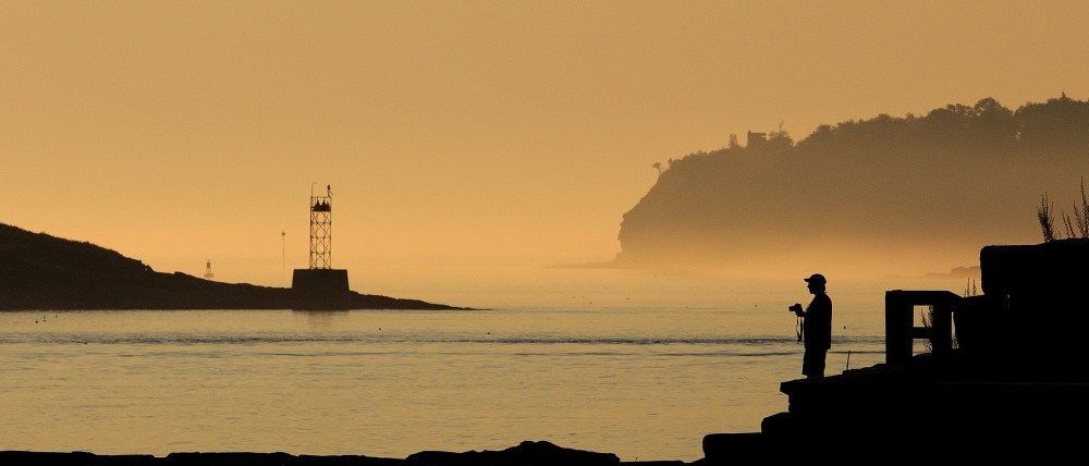 Brian Leonard of South Portland pauses while photographing the sunrise at Spring Point Ledge Light in South Portland on Monday.