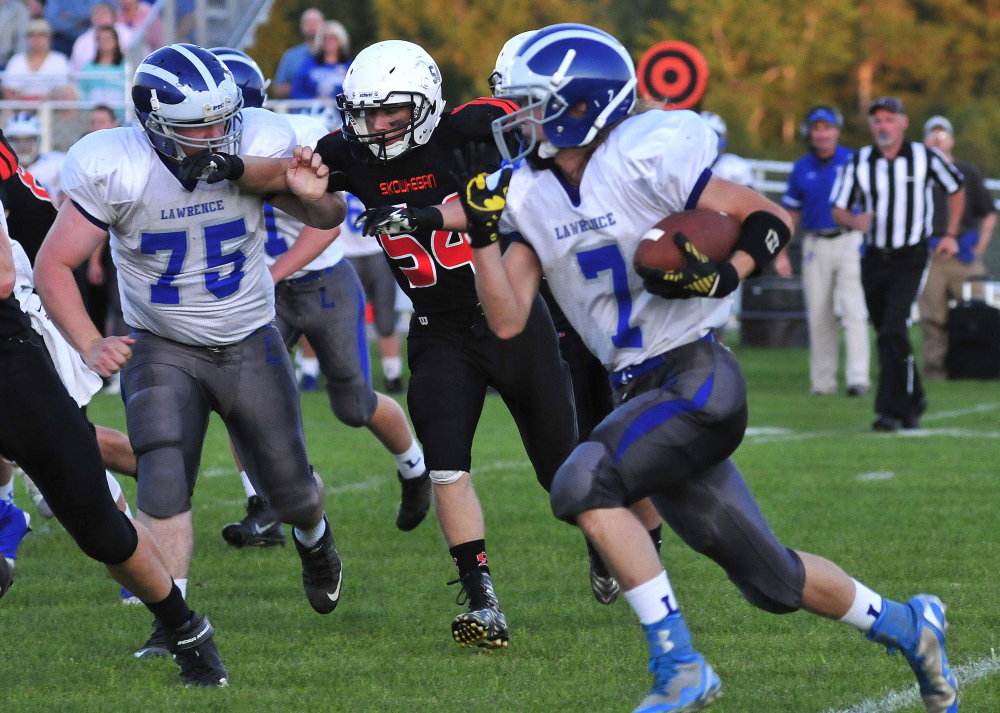 taff photo by David Leaming 
 Lawrence's Walker Thomas (7) gains some yards as Skowhegan's  Braydn Fitzmaurice closes in during a Pine Tree Conference Class B game Friday night at Clark Field in Skowhegan. Lawrence's Robert Zahoransky, left, looks for a block on the play.