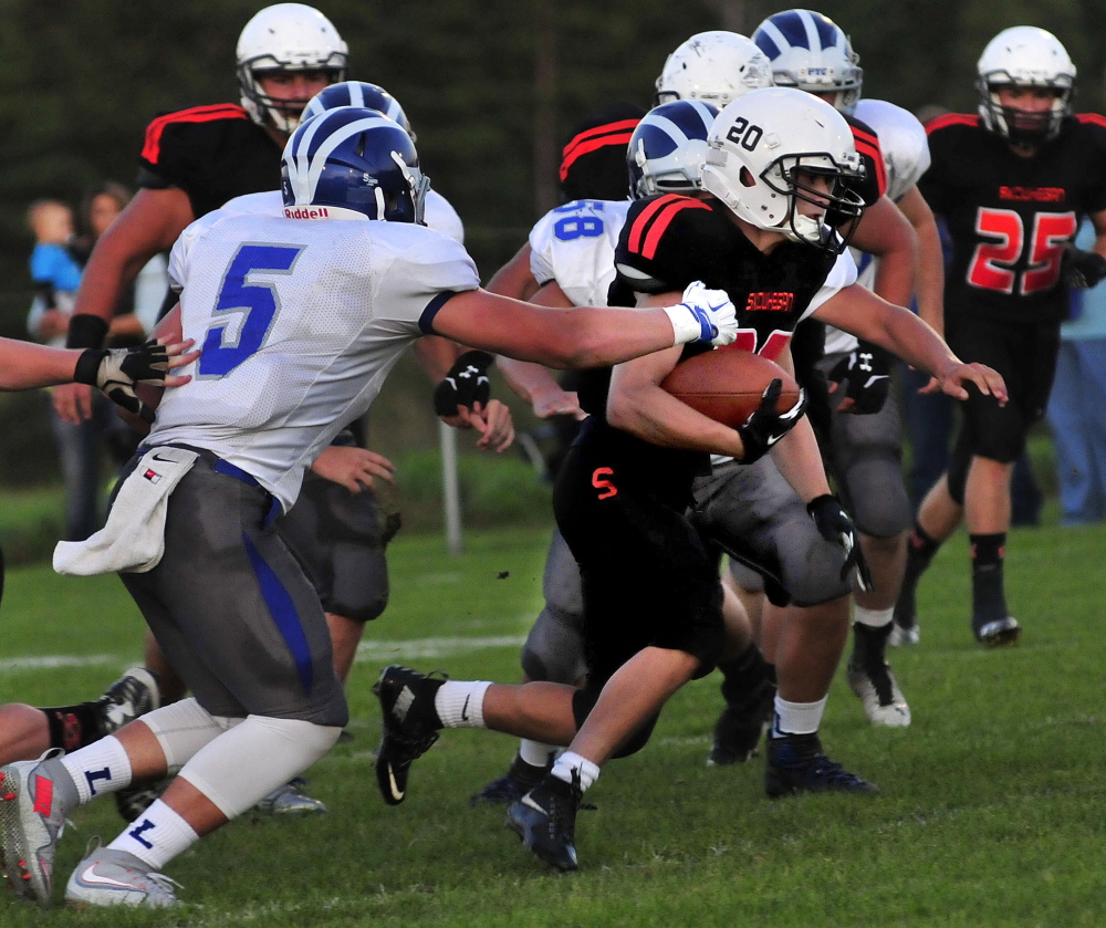 Staff photo by David Leaming 
 Skowhegan's Luke Bolster tries to shed some blockers as Lawrence's Mitchell Cushing goes for the tackle during a Pine Tree Conference Class B game Friday night at Clark Field in Skowhegan.