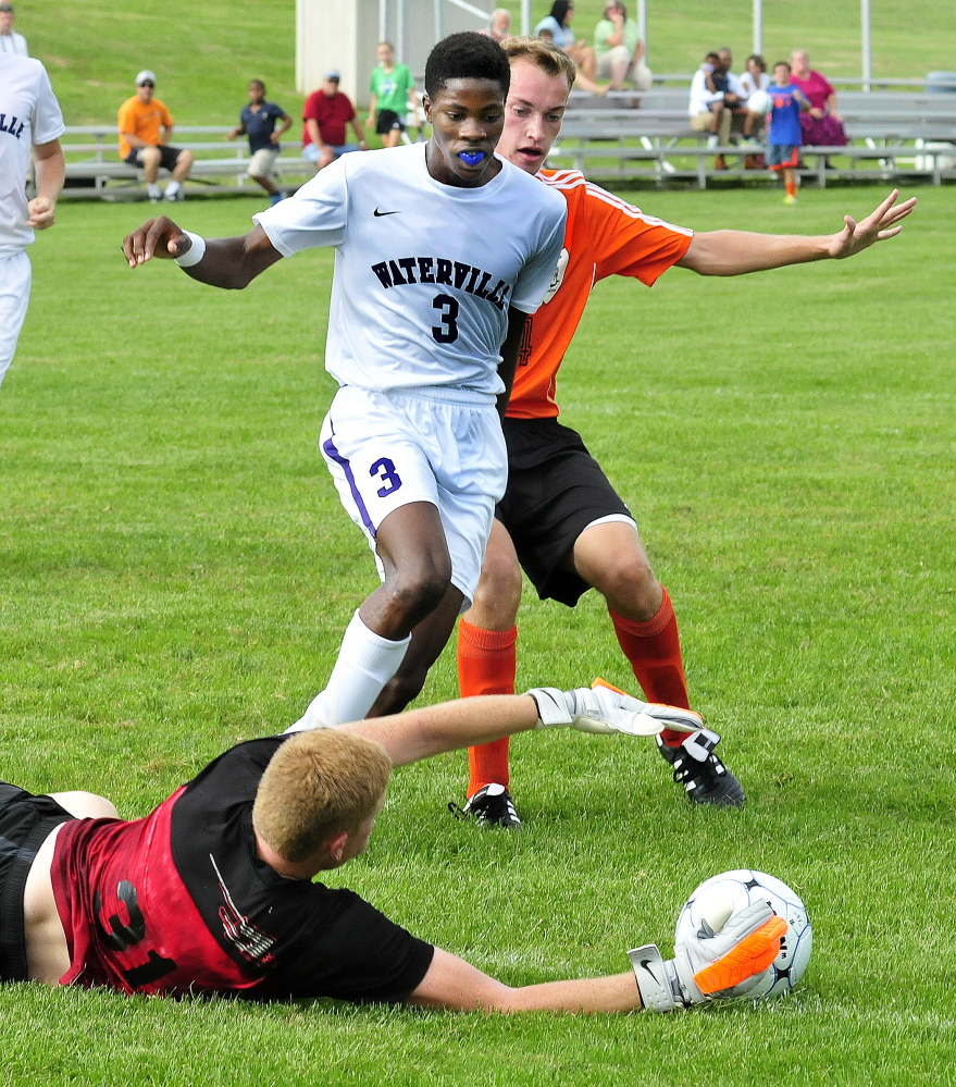 Staff photo by David Leaming 
 Winslow keeper Jake Lapierre makes a diving save against Waterville's Peter Mayhorn as Winslow's Justin Burgher pressures during a game Tuesday at Webber Field in Waterville.