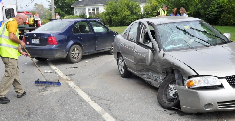 Fairfield Fire Chief Duane Bickford pushes glass off U.S. Route 201 in Hinckley as Fairfield police officer Joe Pelletier gets information from occupants of one of two vehicles involved in an accident on Wednesday. Few details about the accident were available Wednesday.