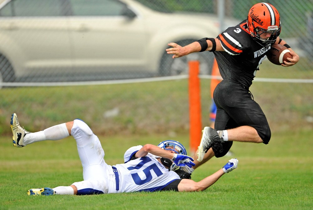 Staff photo by Michael G. Seamans
Madison defender Matt Curtis, bottom, tries to wrap up Winslow running back Dylan Hapworth during a game last Sept. 6 in Winslow.