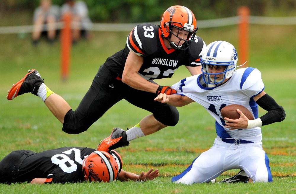 Staff Photo by Michael G. Seamans
Winslow defensive linemen Luke Fedette (28) and Ryan Fedette (33) sack Madison quarterback Chase Malloy during an Eastern C game last Sept. 6 at Poulin Field.