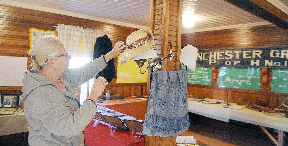 Linda Cobb arranges a bonnet Thursday at the Manchester Grange in preparation for a display by the Manchester Historical Society on Sunday.