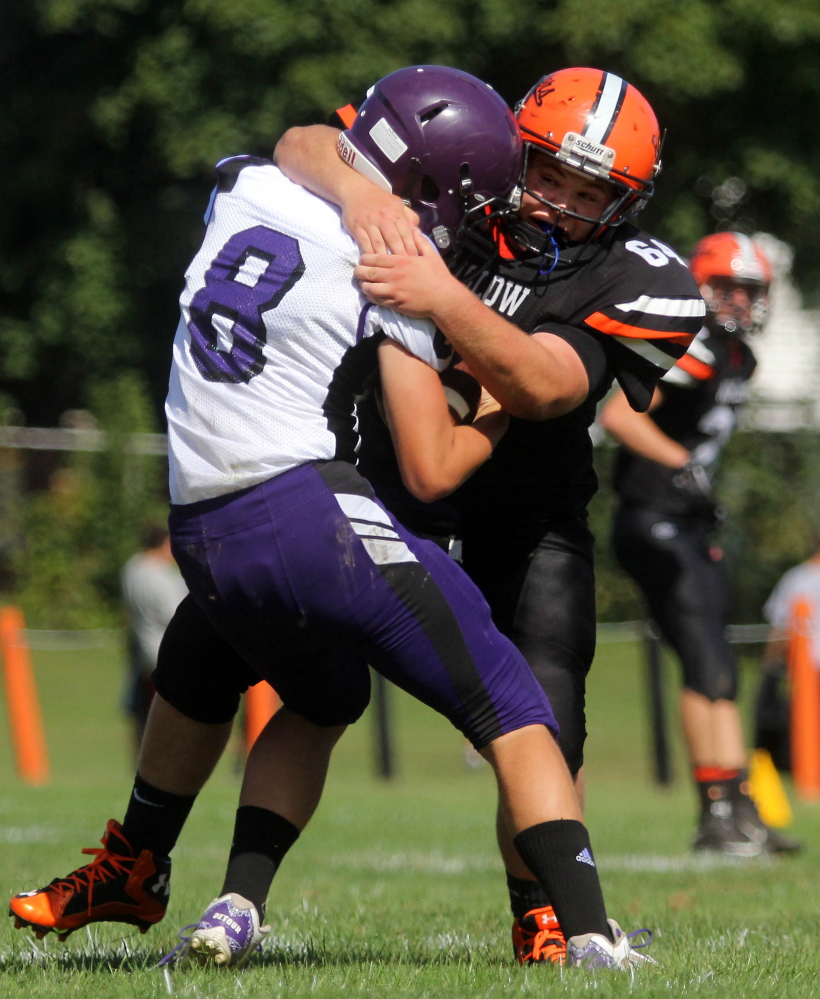 Photo by Jeff Pouland 
 Winslow High School's Chris Jacques wraps up John Bapst quarterback Andrew DeTour during the first half of the Black Raiders' 63-0 win earlier this season.