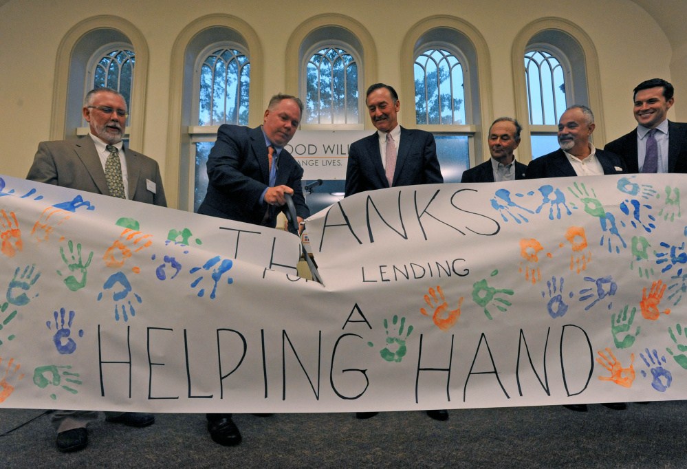 Jack Moore, left center, interim president of the Maine Academy of Natural Sciences cuts the ceremonial banner with Rob Moody, left, interim president of Good Will-Hinckley, and Greg Powell, center, Good Will-Hinckley Board chairman, during an inauguration ceremony Wednesday of the recently completed $7 million worth of renovations on the former Moody School at the Good Will-Hinckley campus. The building is being touted as Maine’s first fully-solar powered academic building and will allow the charter school to more than double its current enrollment.