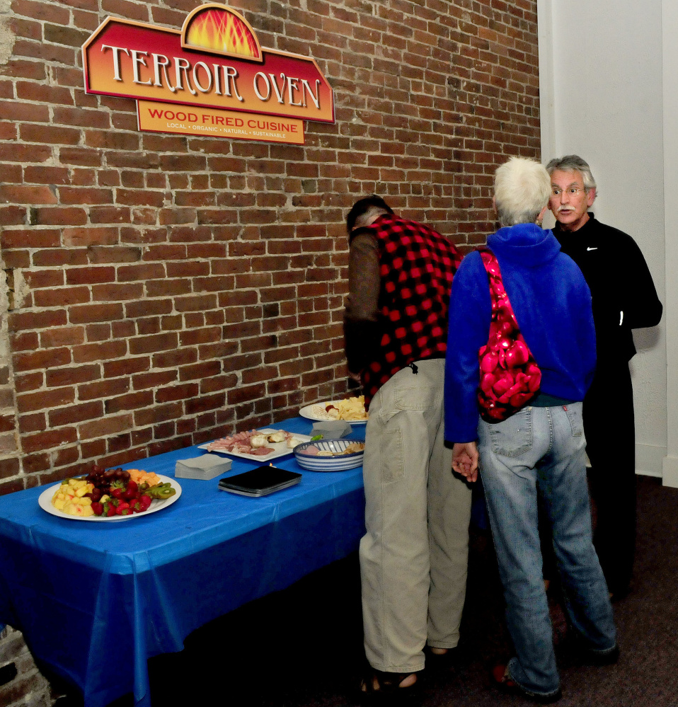 People gather around a table filled with appetizers during a pre-launch party Wednesday for the new Terroir Oven restaurant on Common Street in Waterville. The downtown restaurant is slated to open Dec. 1.