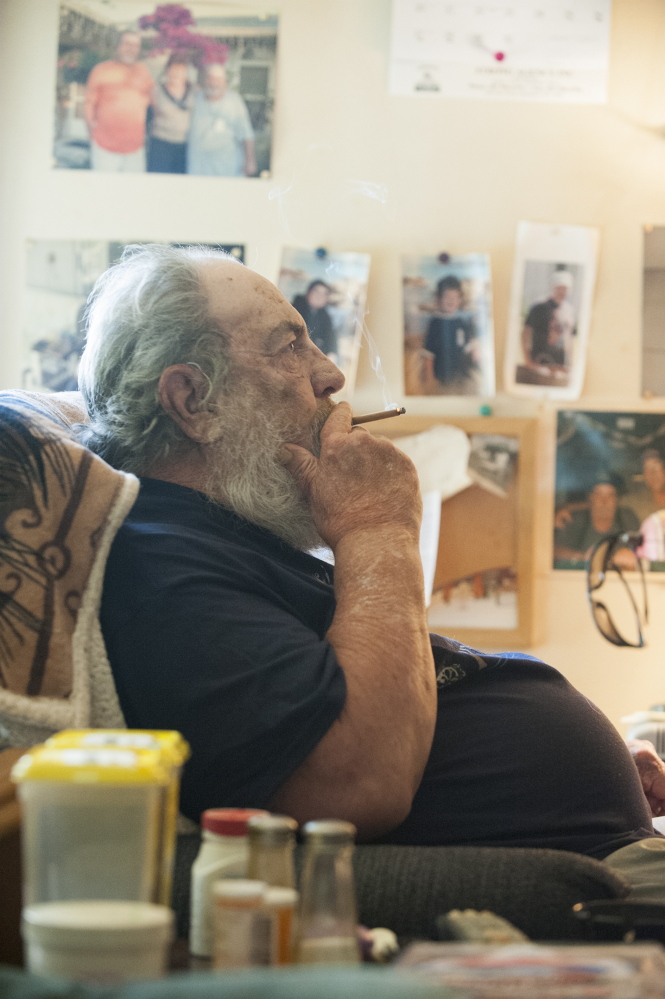 Rockland, Maine--09-01-2015-- Harvey Lembo sits in his living room  in Rockland next to his wheel chair smoking a cigarette on Tuesday. Lembo allegedly shot  Christopher Wildhaber after he broken in and told Lembo he was there to rob him. Lembo has been robbed 5 times in 6 years, until he bought an antique hand gun on Monday. 
 Kevin Bennett Photo