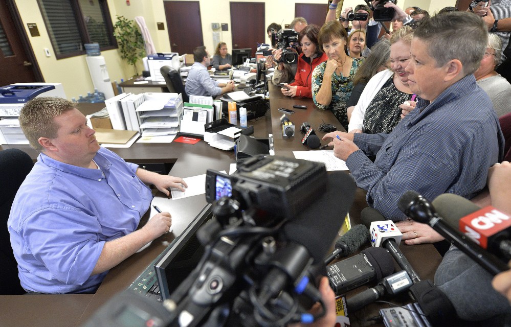Rowan County Deputy Clerk Brian Mason, left, now given the job title, “marriage license deputy,” helps Shannon Wampler-Collins, right, and Carmen Wampler-Collins with a marriage license.