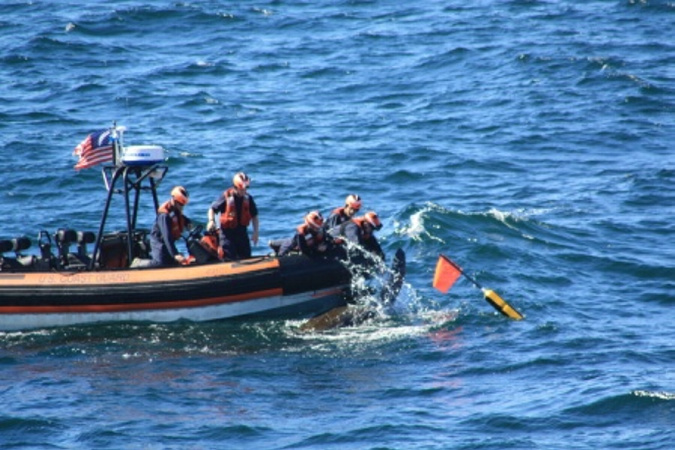 Crew members in a small boat deployed from the U.S. Coast Guard cutter Campbell untangle a 6-foot-long leatherback turtle from fishing line 15 miles off Cape Elizabeth on Sunday. After cutting the line, the crew watched as the turtle swam away to the open sea.