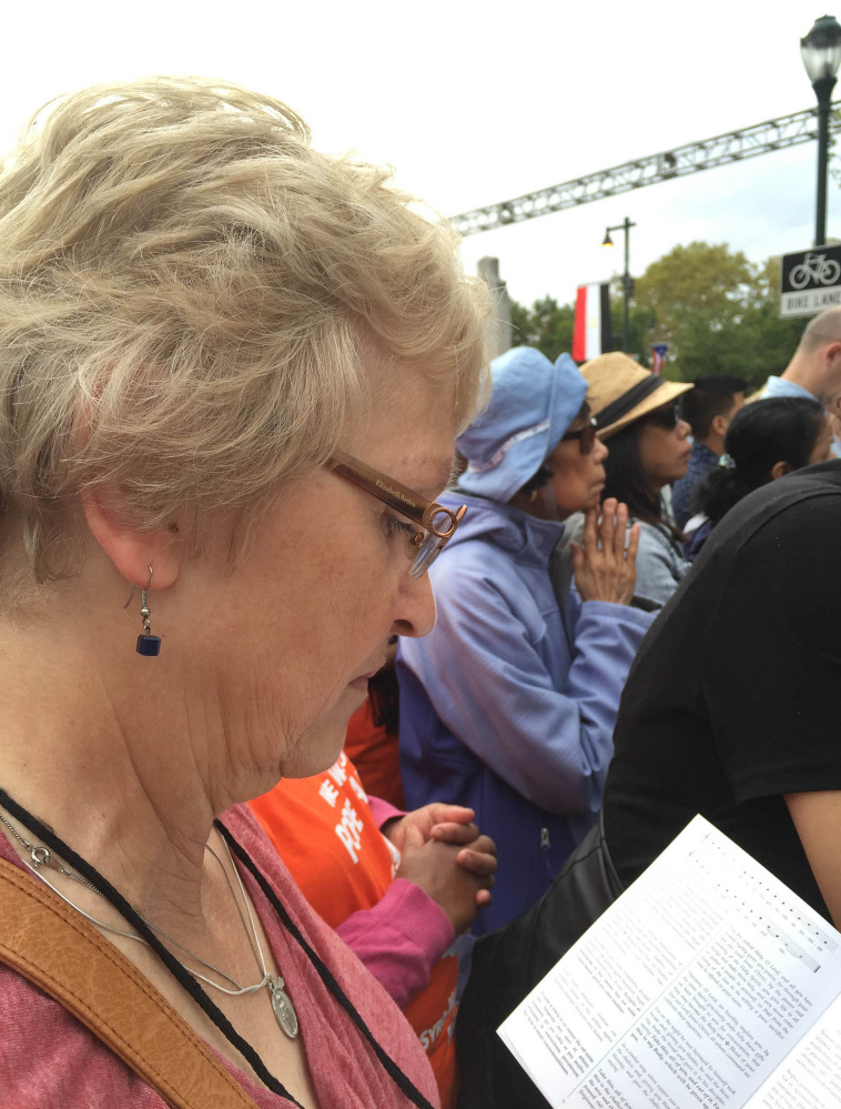 Kay Saucier of Levant, on a pilgrimage organized 
by the Roman Catholic Diocese of Portland, reads a translation of a Latin prayer during the Mass that Pope Francis celebrated in Philadelphia on Sunday.