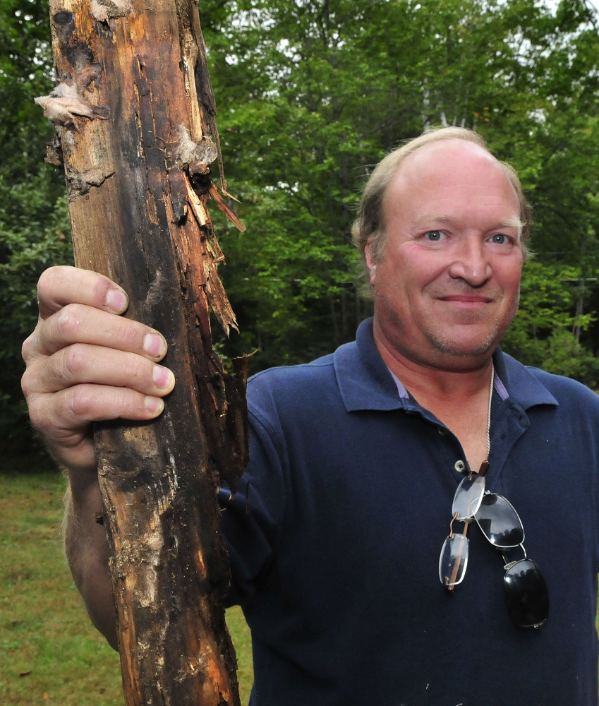 Brian Jacques holds a rotted piece of 2-by-6 framing lumber that was pulled from the Oakland home of his sister and brother-in-law, Janet and Chris Weeks.