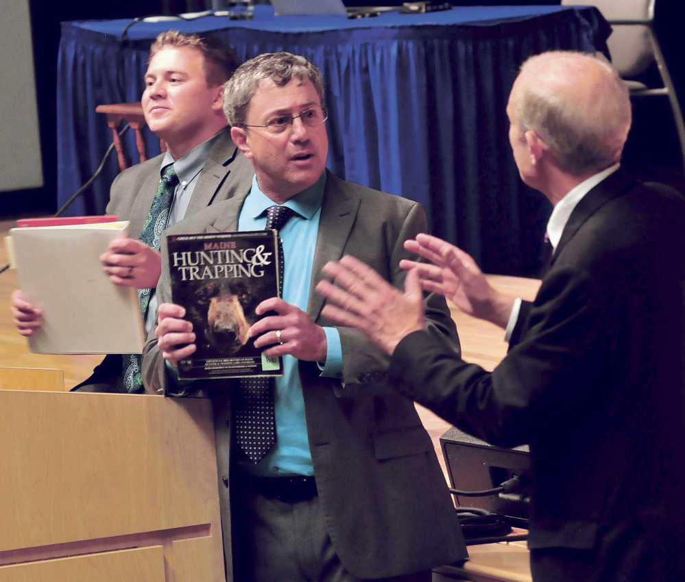 Attorney Lawrence Bloom, center, holds a hunting regulation book after arguing his client is innocent of a hunting violation following an appeal hearing with the Maine Supreme Judicial Court at Mt. Blue High School in Farmington on Wednesday. Attorneys Francis Griffin, left, and Paul Mills listen.